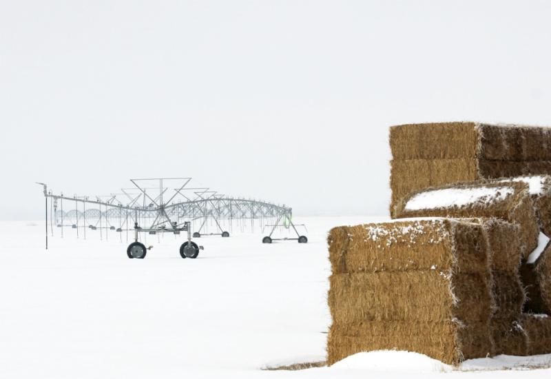 Snowy field with pivot and hay bales