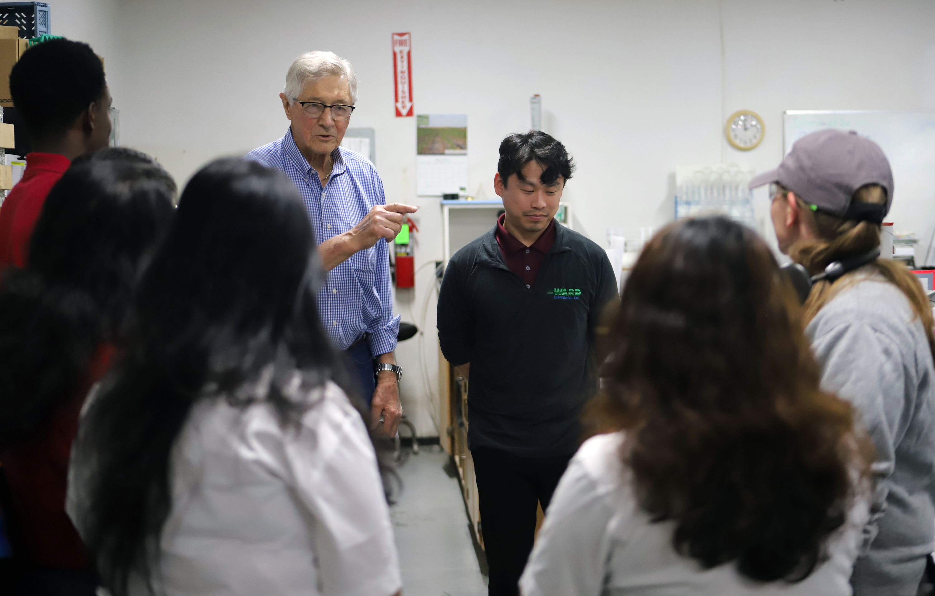 Group of people in a lab setting, one man speaking, others listening attentively.