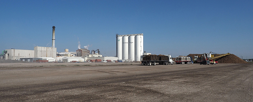 factory in distance with trucks in front area