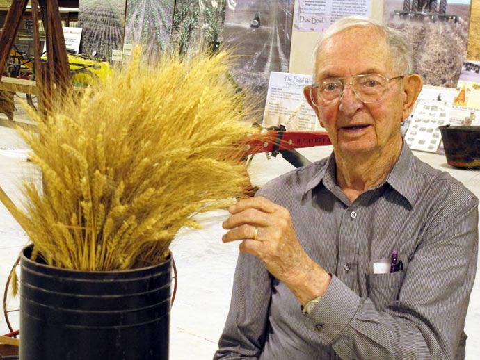 man sitting next to wheat in a bucket