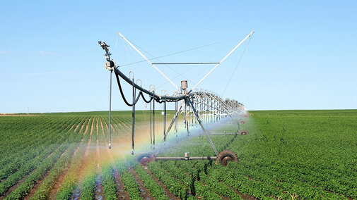 irrigation pivot creates a rainbow in a field.