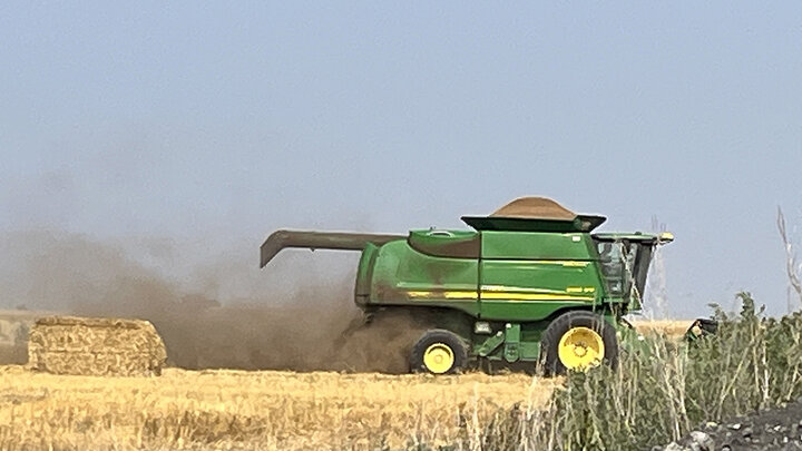 combine with black dust behind it in wheat field