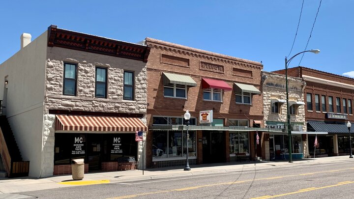 Historic downtown storefronts under a bright blue sky, featuring brick and stone façades.