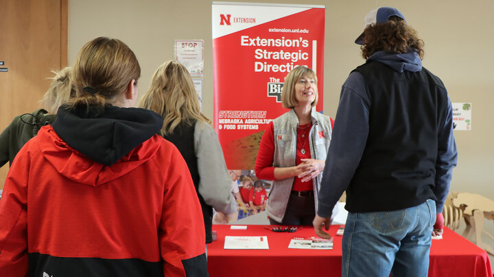 woman at booth talks with students about college