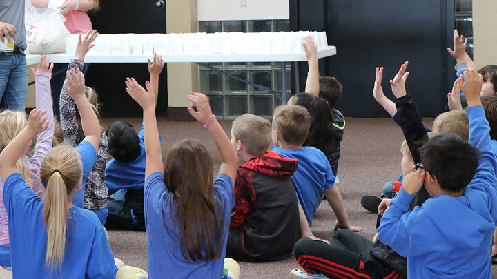 children sitting on floor with hands raised