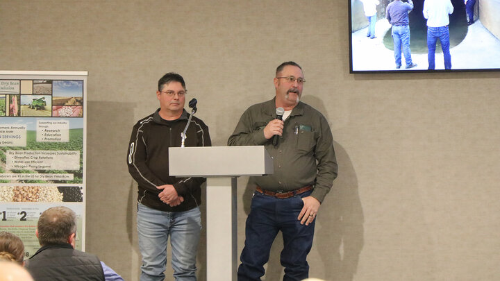 two men at a podium speaking to audience
