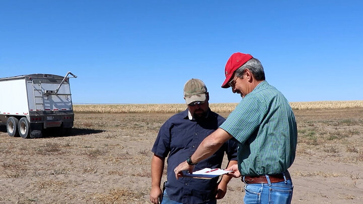 two men in field talking 