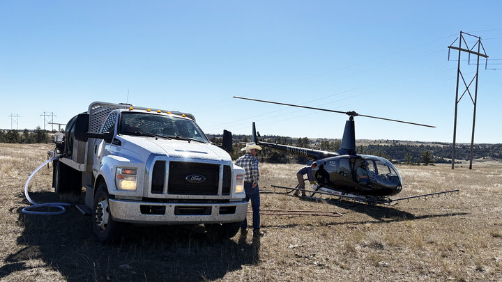 Truck brings herbicide to helicopter to spray invasive grass