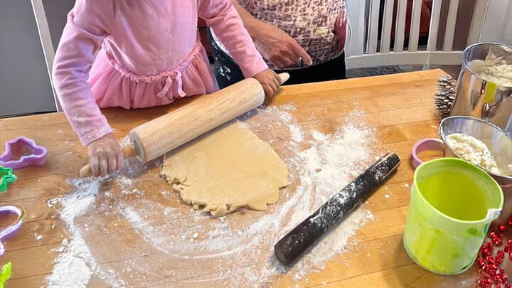 child rolling out cookie dough