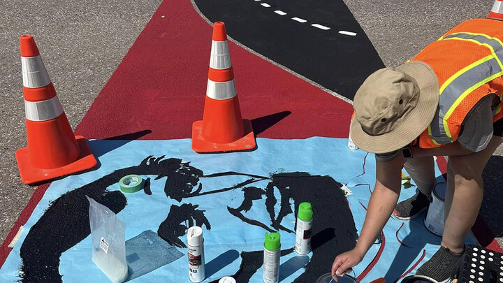 A person paints lincoln's face on artsy crosswalk