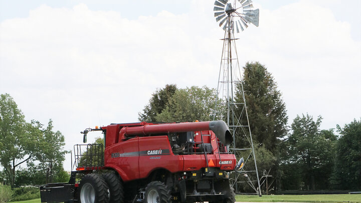 red combine in front of windmill