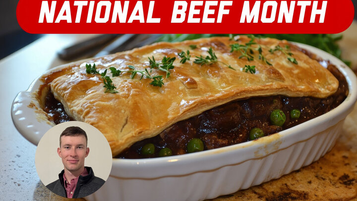 Beef pot pie with golden crust, peas, and thyme garnish in a ceramic dish on a countertop.
