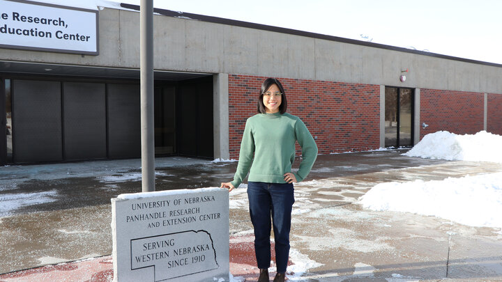 woman standing by signage outside of building