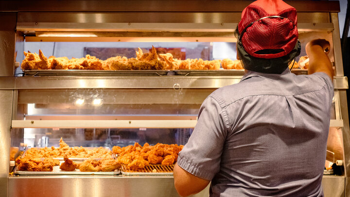 person picks up fried chicken at fast food venue