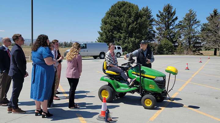 man showing high schoolers self guided mower