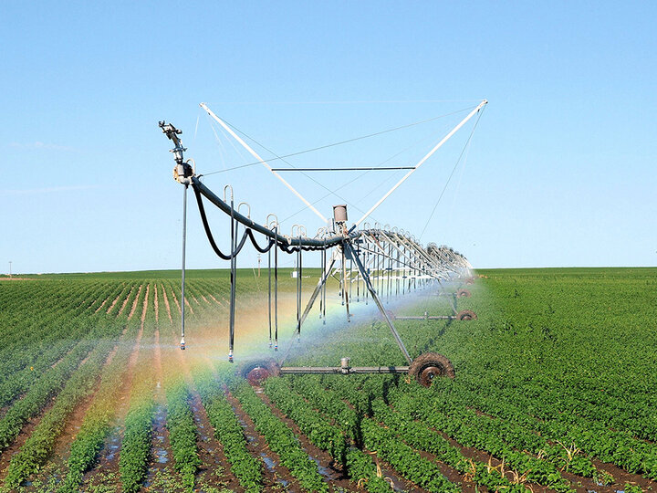 irrigation pivot creates a rainbow in a field.