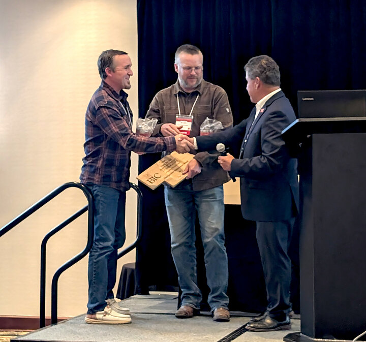 two men receive an award from another man